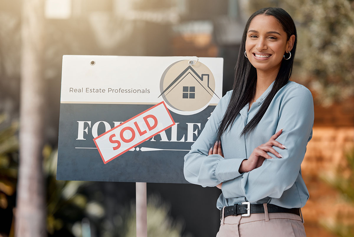 Realtor Beside A Sold Sign Thanks To Her Real Estate Newsletter Program
